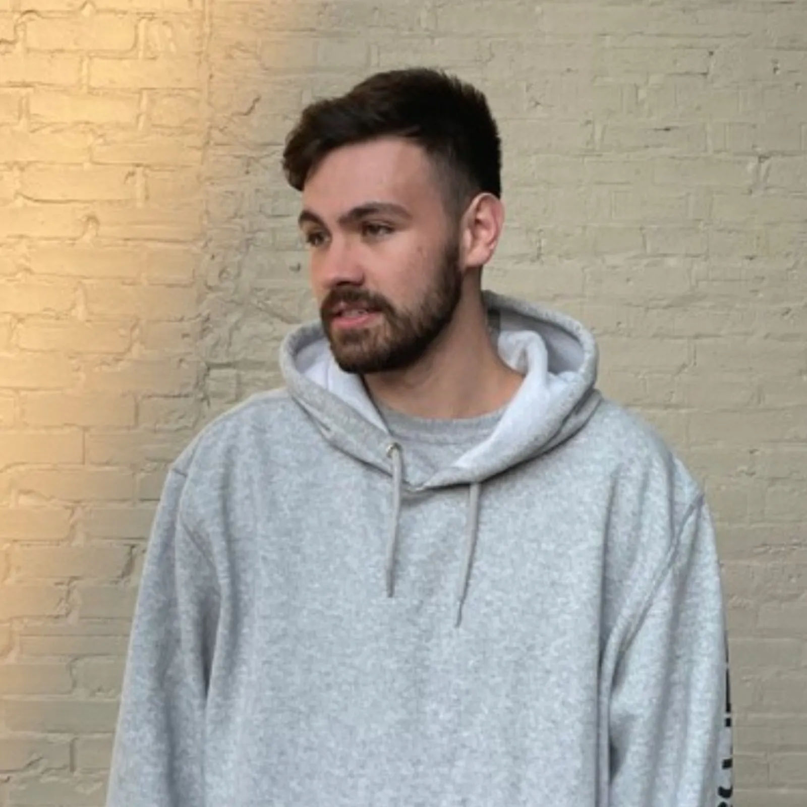 Image of Narcis Baraic with short dark hair and beard wearing a light grey hoodie standing against a beige brick wall.