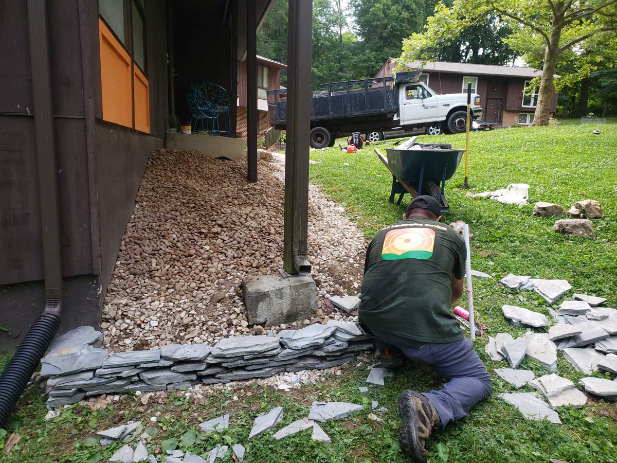 SLS employee laying stones around flower bed