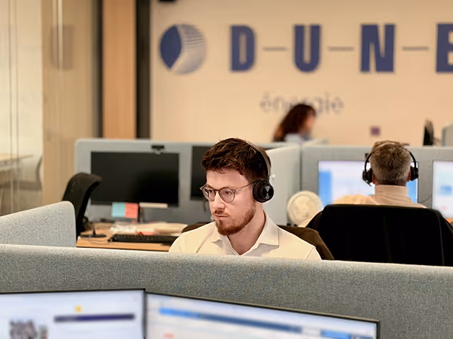 Équipe DUNE Energie au travail dans l'open space avec le logo de la marque au mur