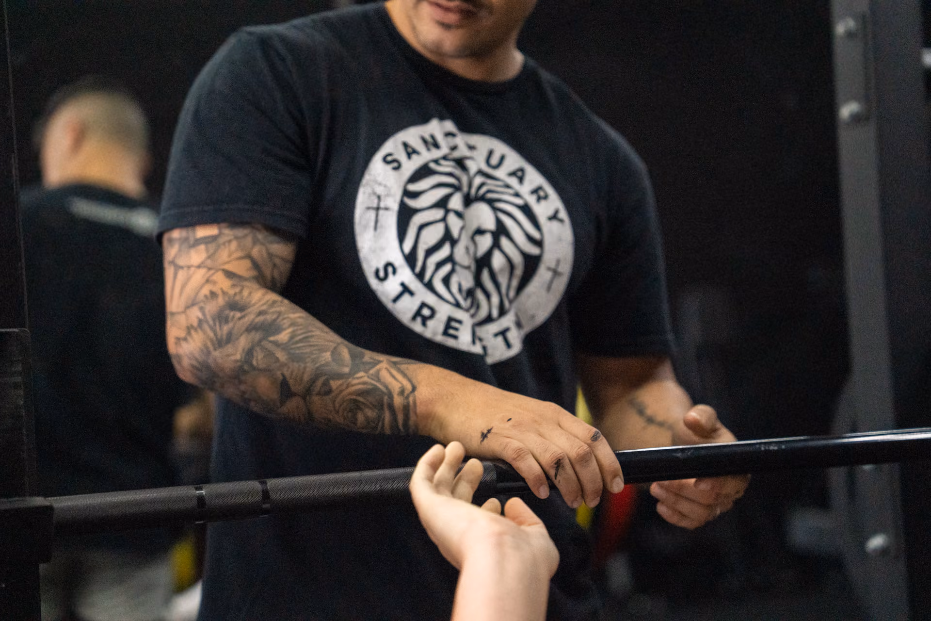 A personal trainer adjusting a client's grip on a barbell at Sanctuary Strength in Franklin, TN