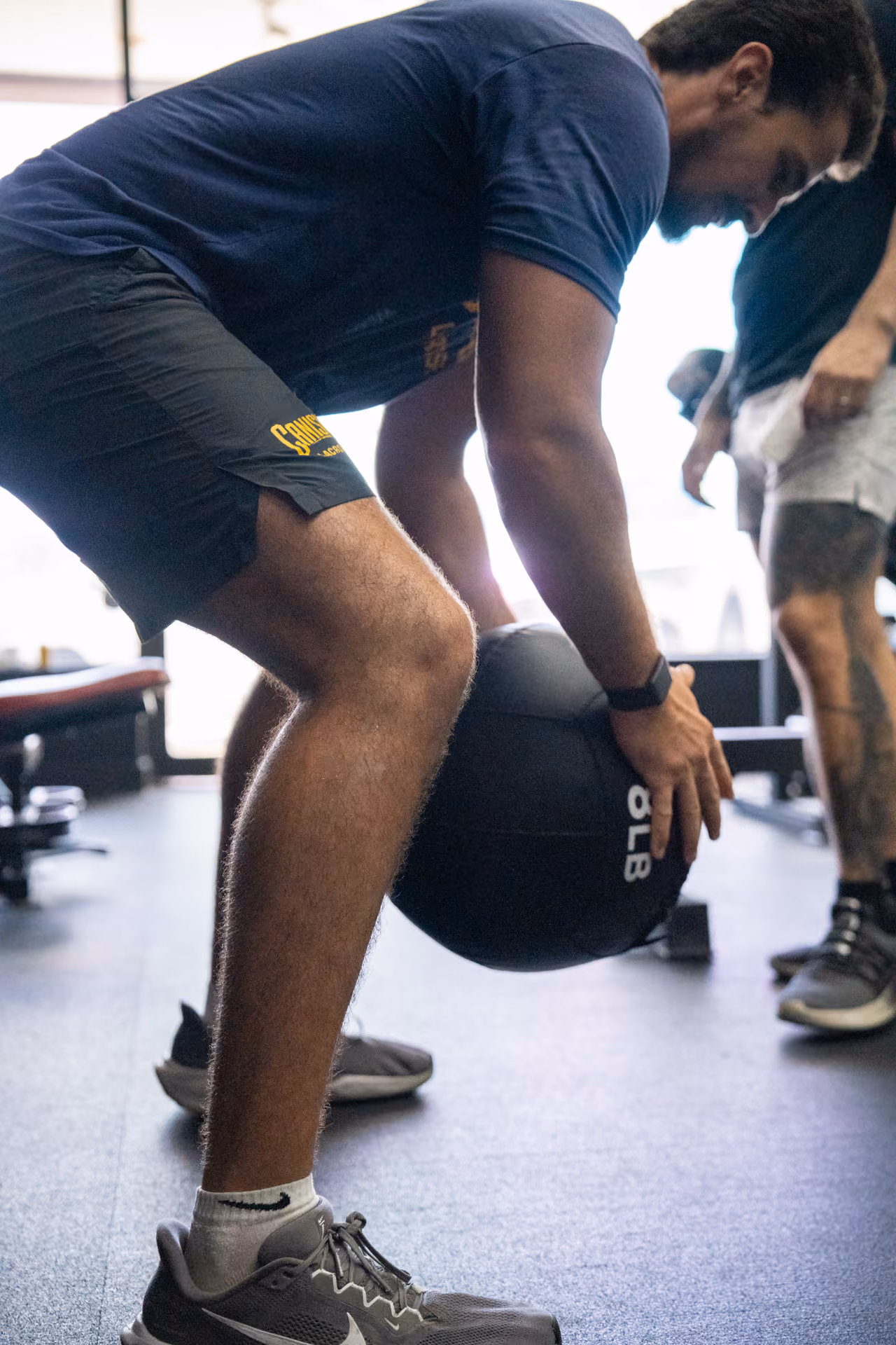 A client lifting a medicine ball while a personal trainer coaches at Sanctuary Strength in Franklin, TN