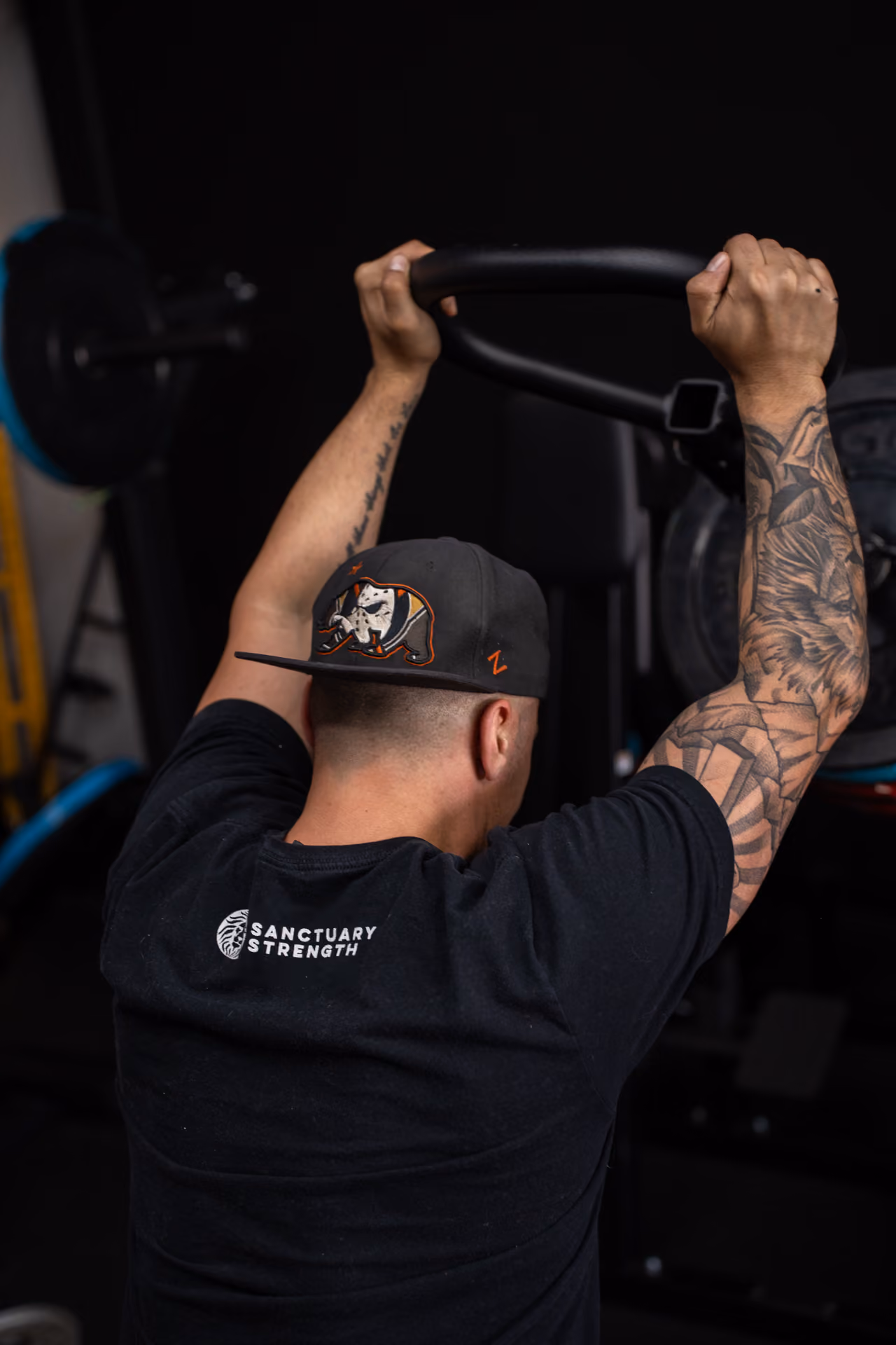 A Sanctuary Strength trainer gripping an overhead cable attachment during a workout in Franklin, TN