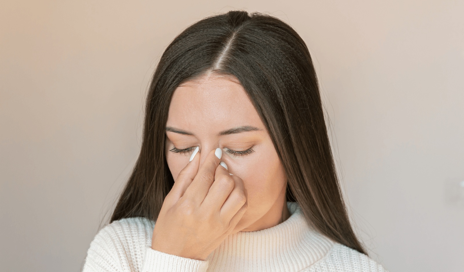 Woman touching her nose due to sinus discomfort, a common symptom of a nasal polyp, looking for guidance available from the best ENT doctor in Torrance.