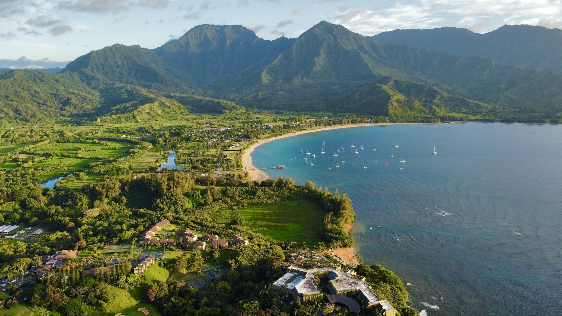 Aerial view of Hanalei Bay on Kauai's north shore, with boats moored off the crescent beach