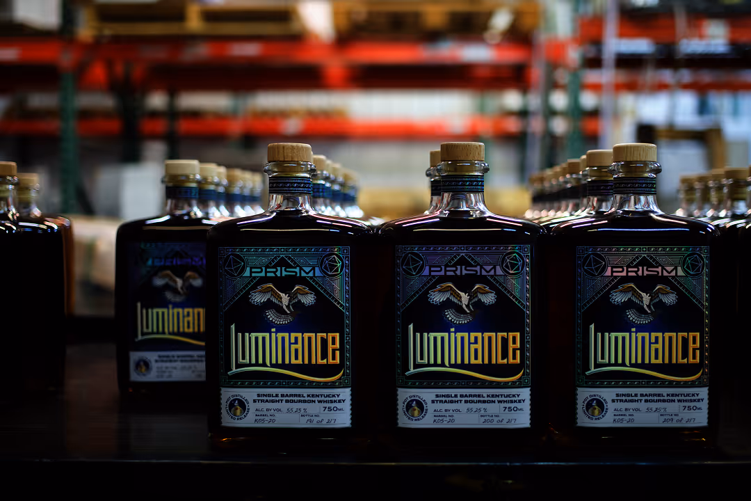 A lineup of finished Luminance Paradox and Prism single barrel bourbon bottles.