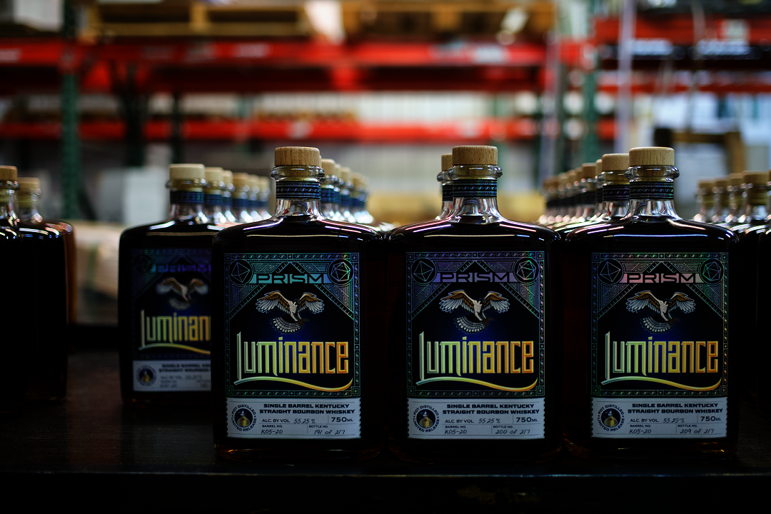 A lineup of finished Luminance Paradox and Prism single barrel bourbon bottles.