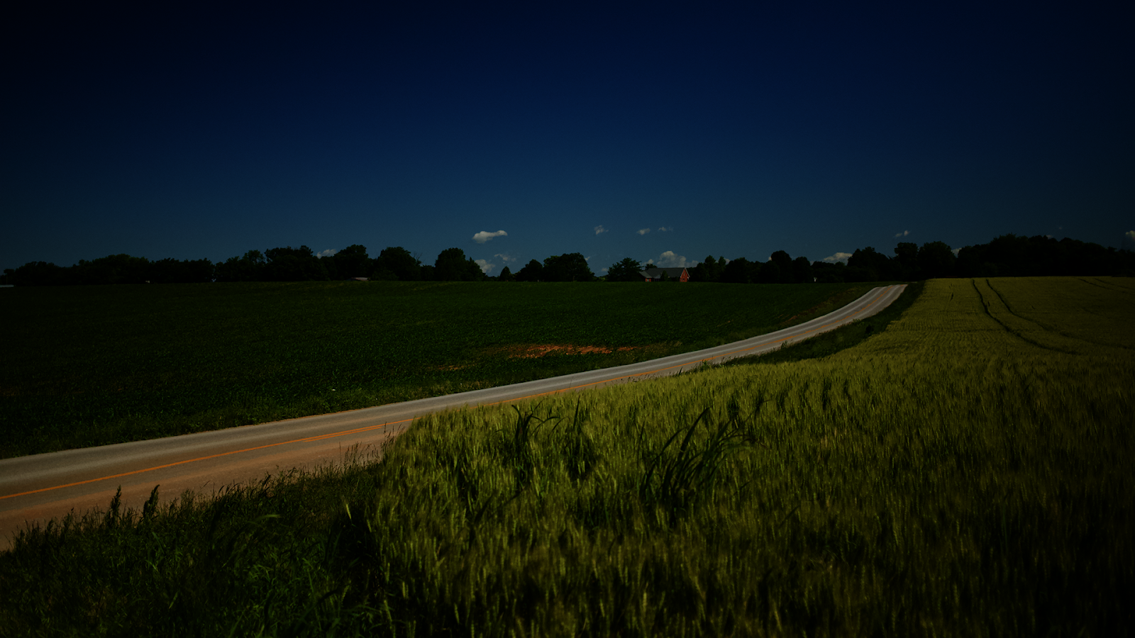 Country road winding through Kentucky farmland at dusk, white fences lining the path toward the horizon