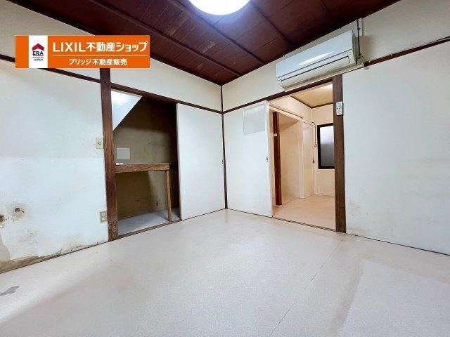 Interior room with white walls, wooden ceiling beams, air conditioning unit, and LIXIL real estate company logo overlay
