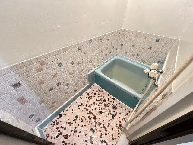 Japanese-style bathroom with decorative tiled walls and turquoise bathtub