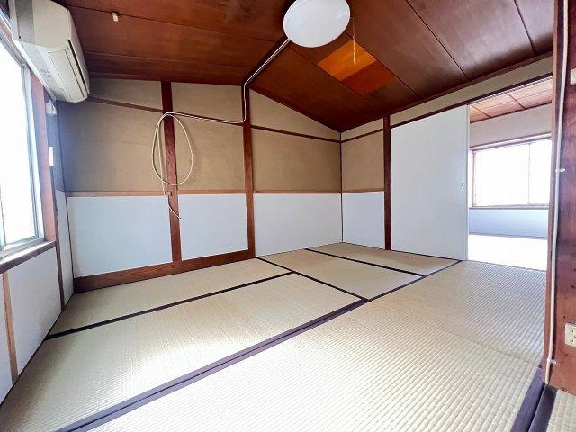 Large tatami room with wooden ceiling beams, air conditioning unit, and natural lighting