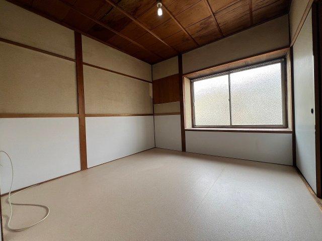 Japanese-style room with wooden ceiling, white walls with brown trim, and large window