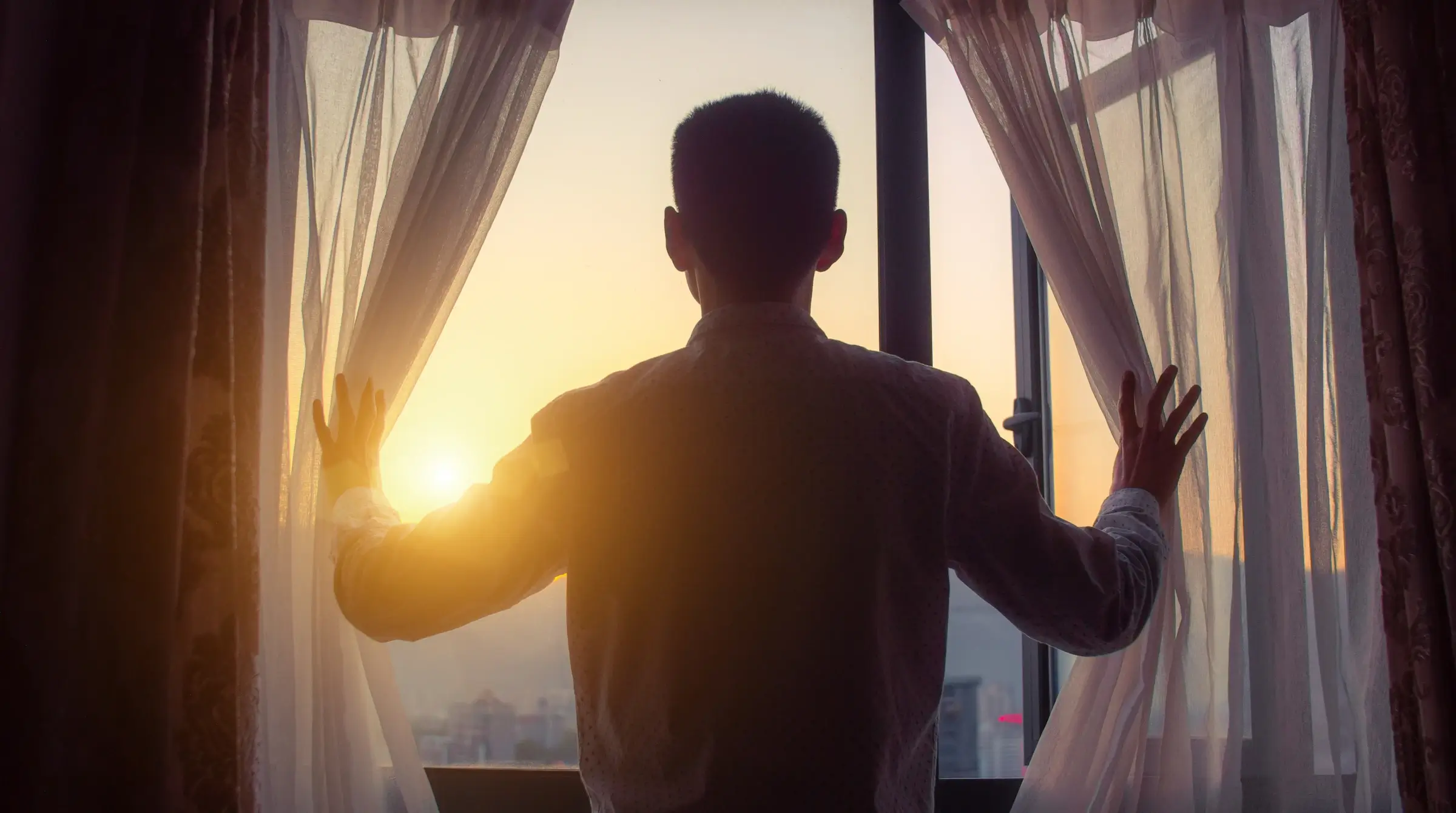 A person looking out the window at the sunset