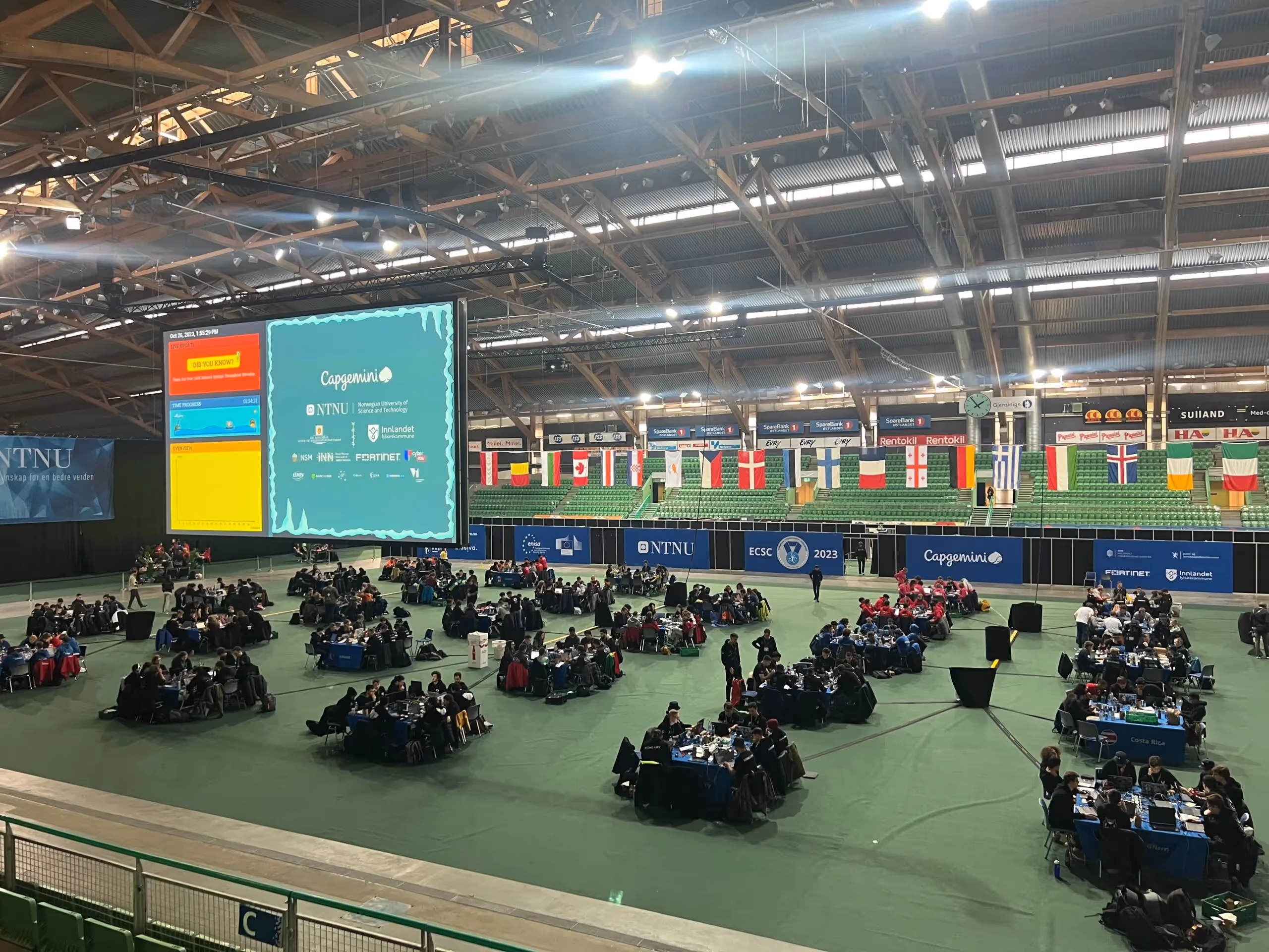 a large room with a large screen and people sitting at tables