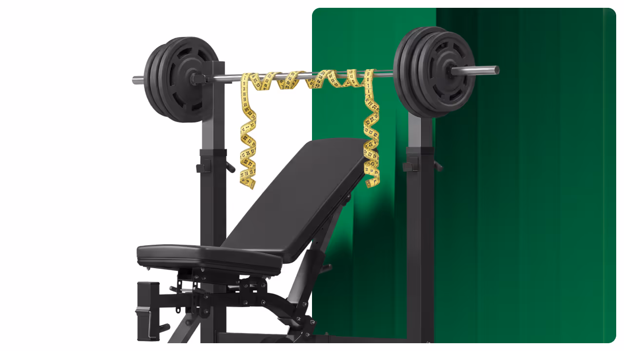 Weight bench with barbell, plates, and a yellow measuring tape draped over the barbell.