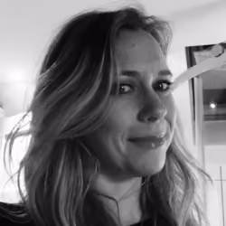 Black and white close-up portrait of a woman with long hair smiling slightly, indoors.
