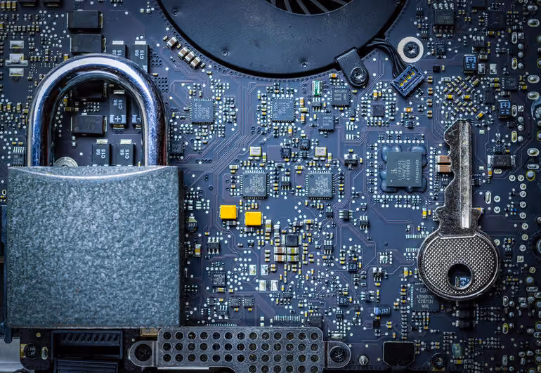 Close-up of a padlock and key on a computer circuit board symbolizing cybersecurity.