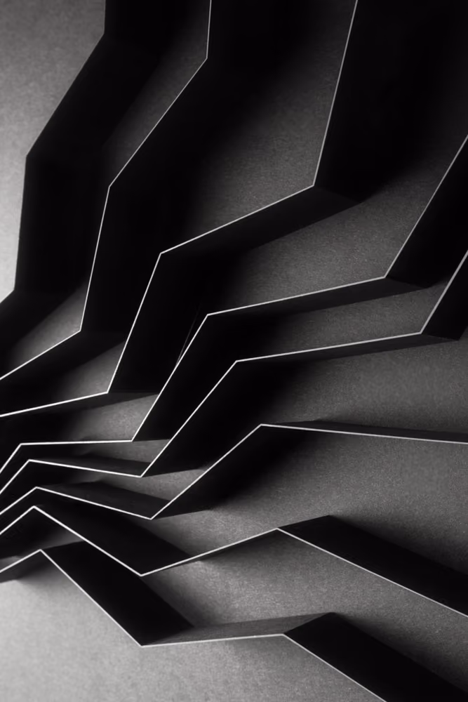 Abstract black zigzag layered paper art with sharp edges and contrasting light and shadows.