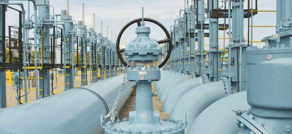 Large industrial pipeline system with valves and control wheels outdoors under a cloudy sky.