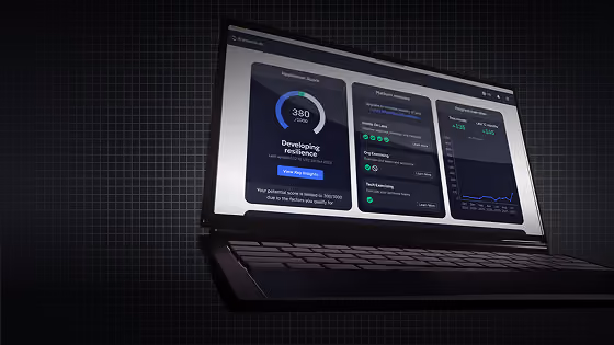Laptop displaying a dashboard with resilience score, platform modules, and performance graphs on screen.