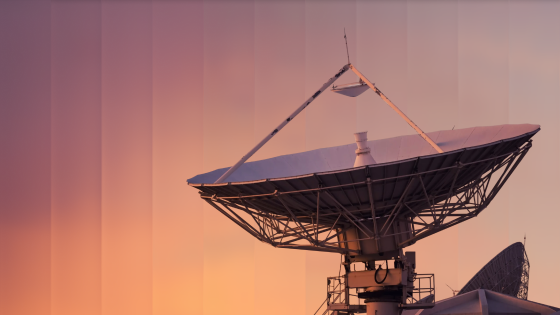 Large satellite dish antenna against a sunset sky with warm orange and purple hues.