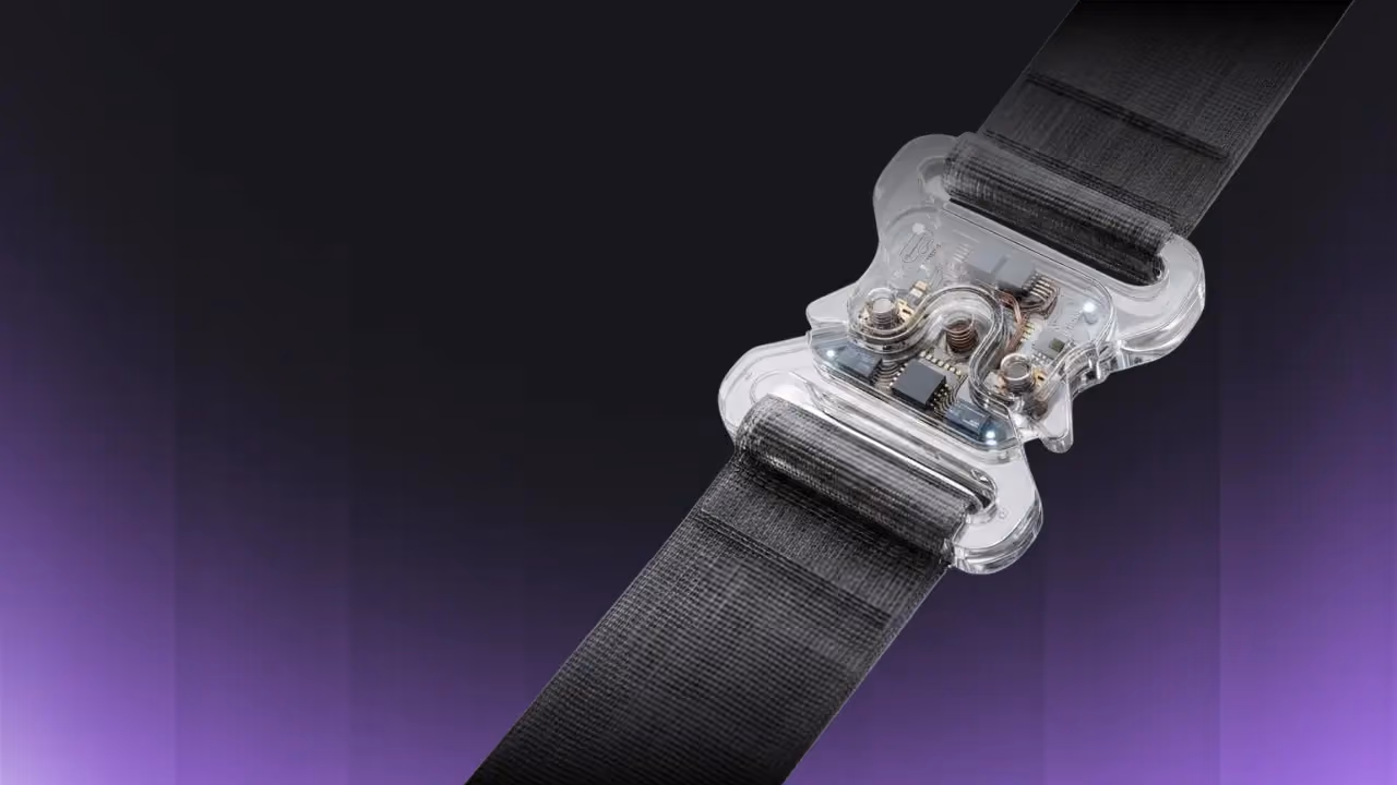 Close-up of a black strap with a transparent smart buckle featuring visible internal electronic components against a gradient dark to purple background.