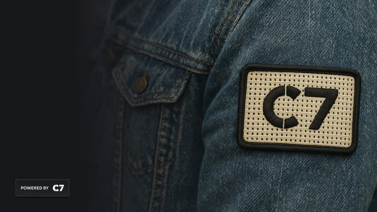 Embroidered patch with C7 on denim jacket sleeve near buttoned chest pocket.