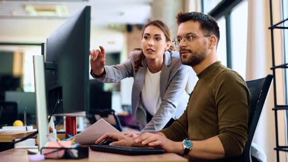 Two colleagues reviewing a desktop computer screen.