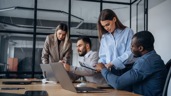 Four colleagues discussing information around a laptop.