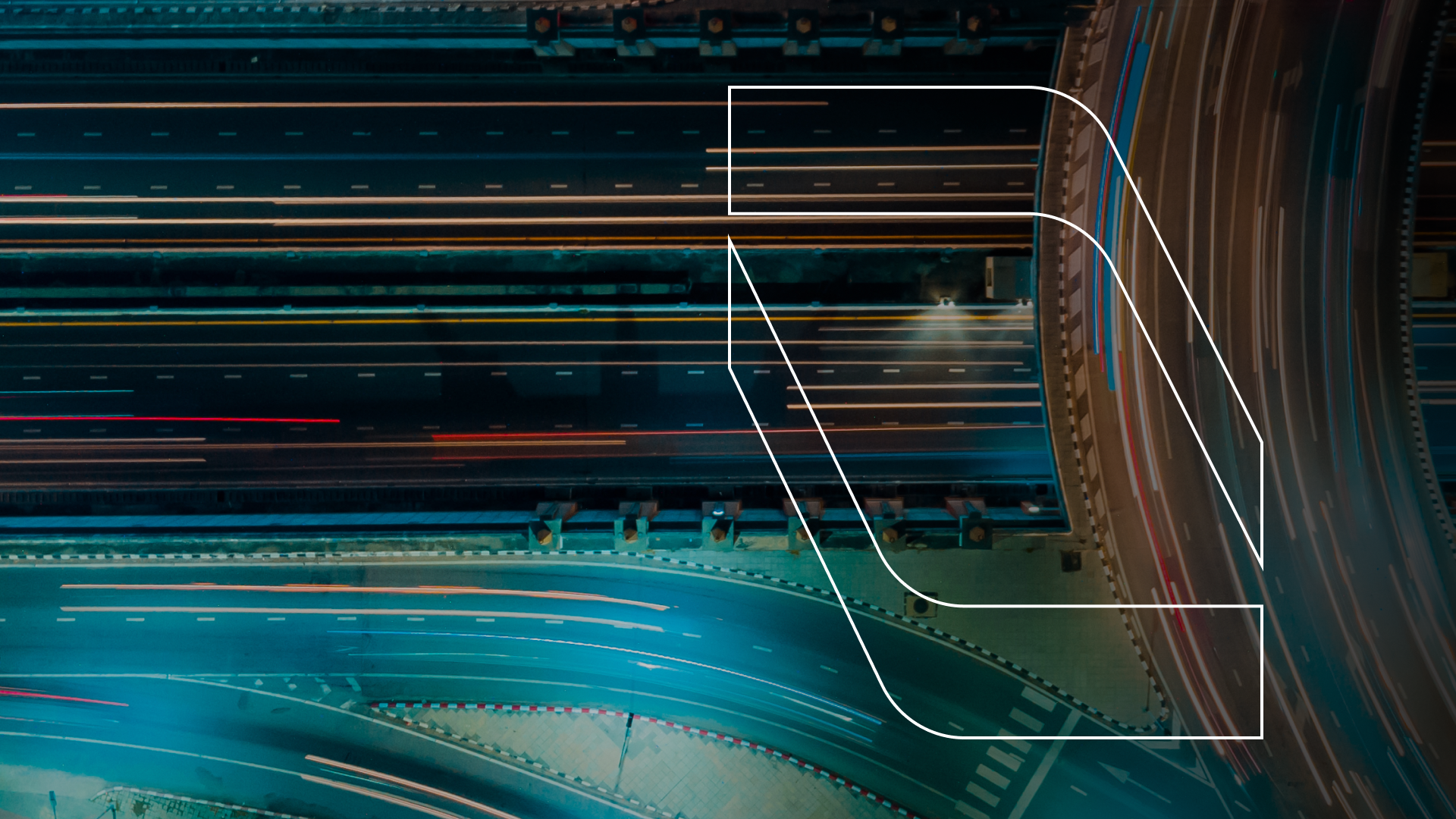 Aerial night view of a multi-lane curved highway with light trails from moving vehicles.