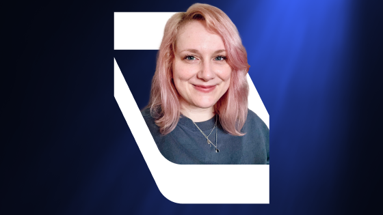 Smiling woman with pink hair against a dark blue background with white geometric shapes.