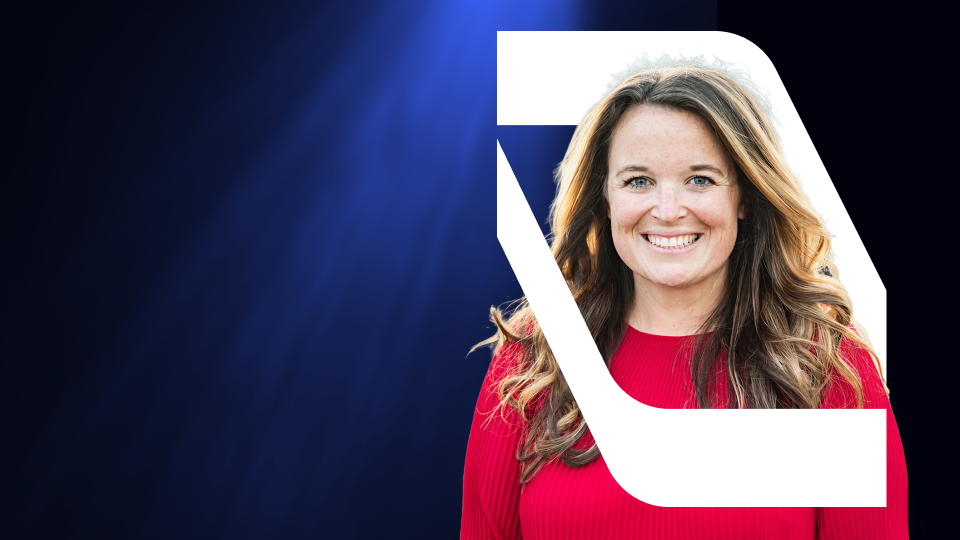 Smiling woman with long wavy hair wearing a red top on a dark blue gradient background