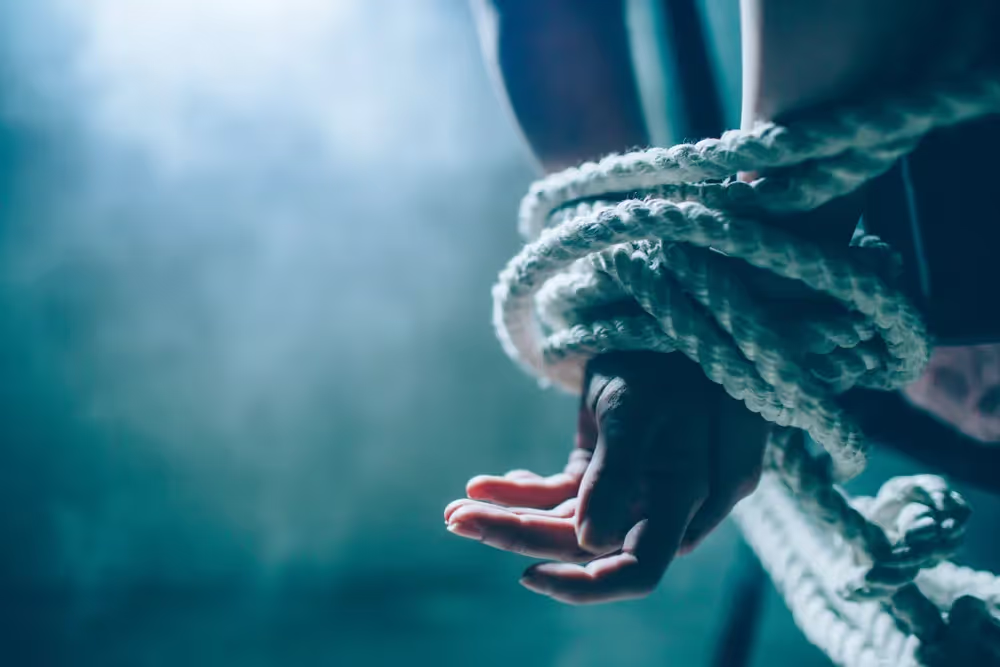A person with their wrists bound by rope.