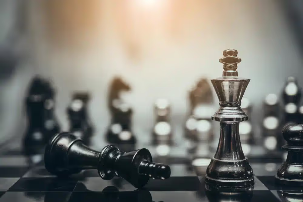 Standing chess king beside a fallen chess piece.