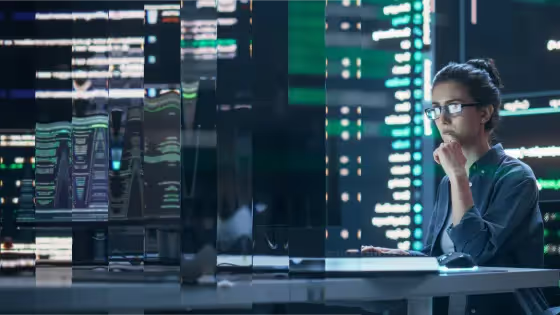 Analyst examining multiple screens in a blue-lit operations room.