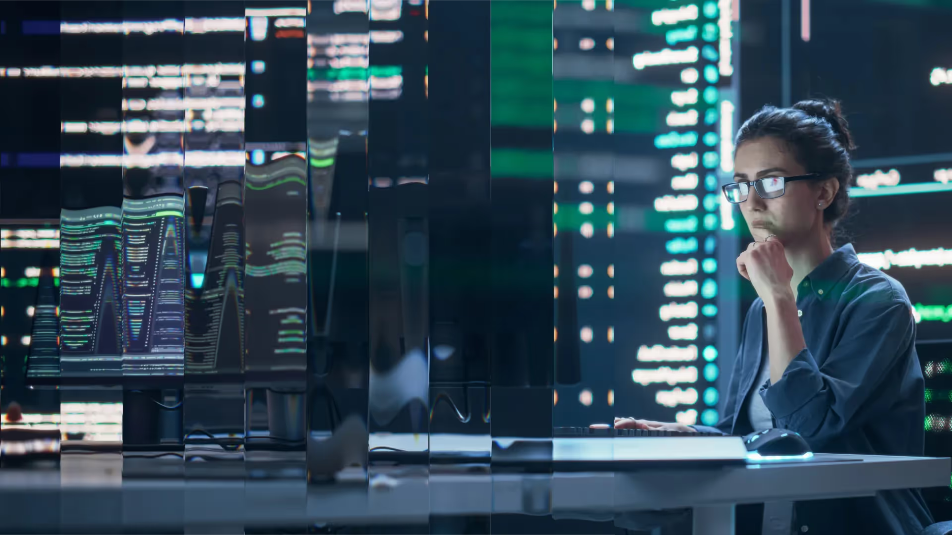 Analyst examining multiple screens in a blue-lit operations room.