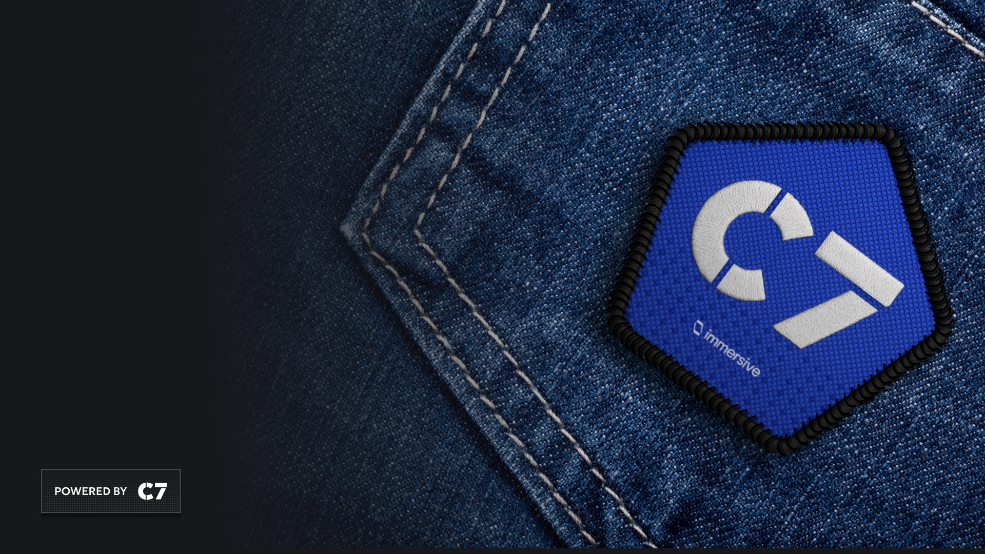 Blue pentagonal patch with white C7 logo and text 'immersive' on denim fabric background.