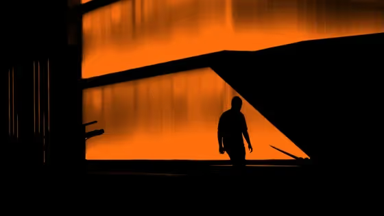 Silhouette of a person against an orange-lit building.