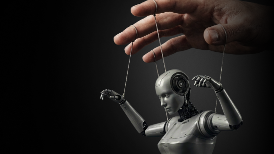 Human hand controls a female robot puppet by strings against a dark background.