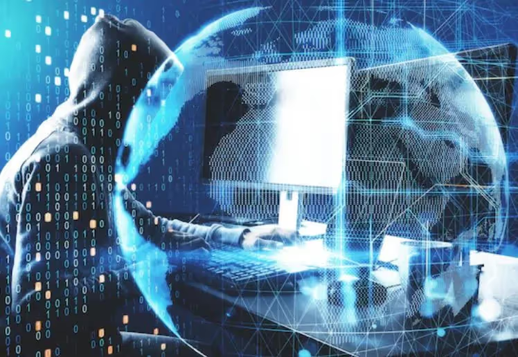 Hooded figure at a computer with a digital globe and binary code overlay.