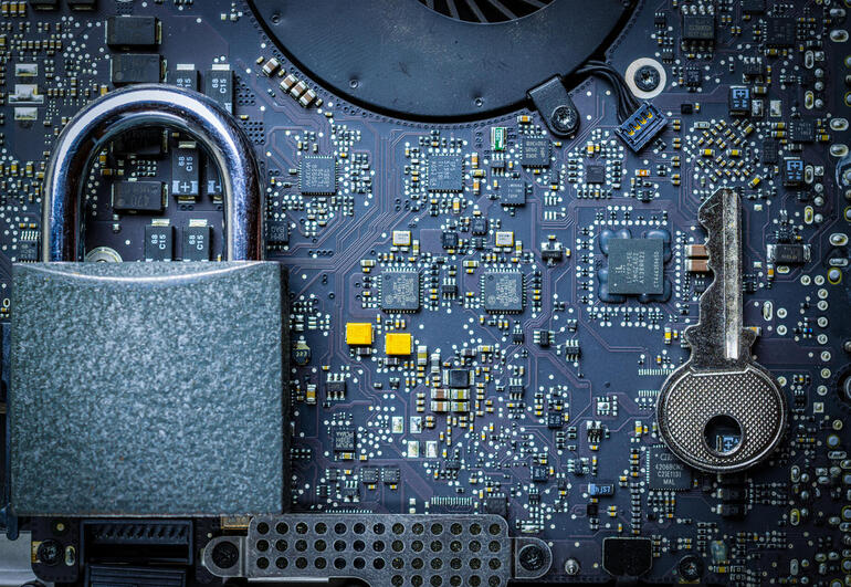 Close-up of a padlock and key on a computer circuit board symbolizing cybersecurity.