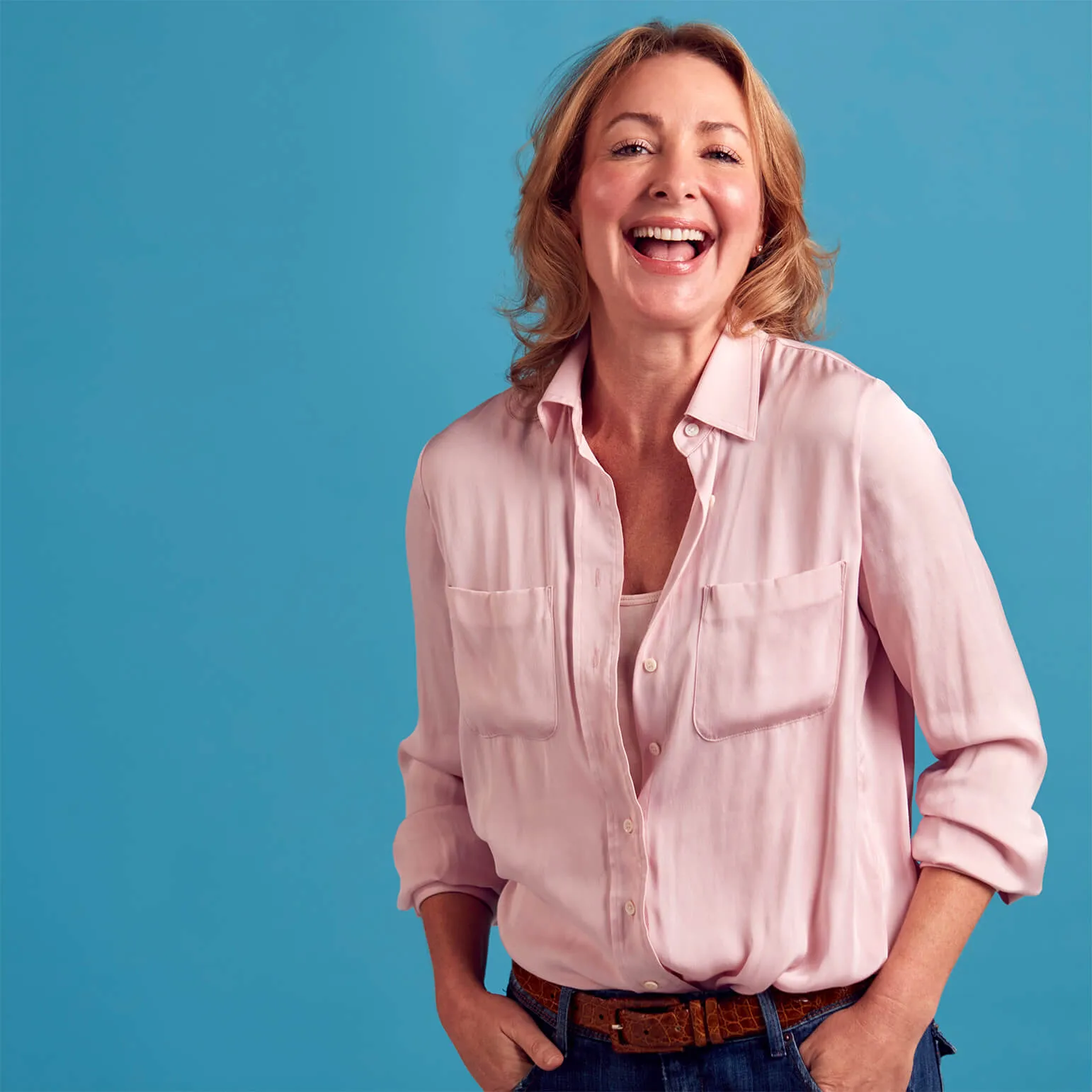 Woman in pink shirt smiling against blue background