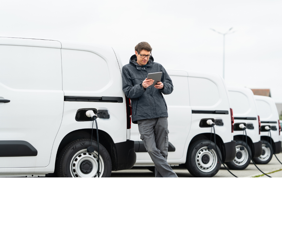 Fleet manager checking a tablet beside a row of vans