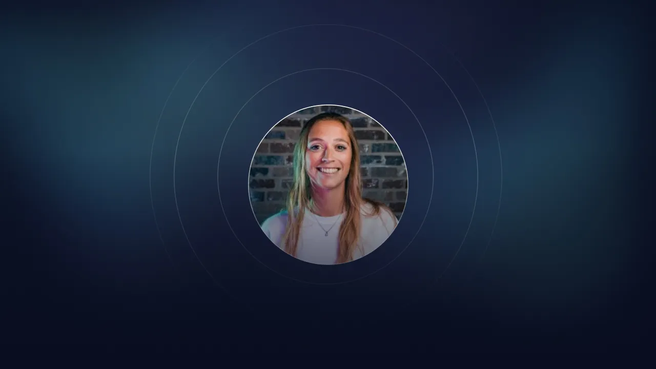 Circular portrait of a smiling woman in front of a brick wall, framed by rings on dark blue