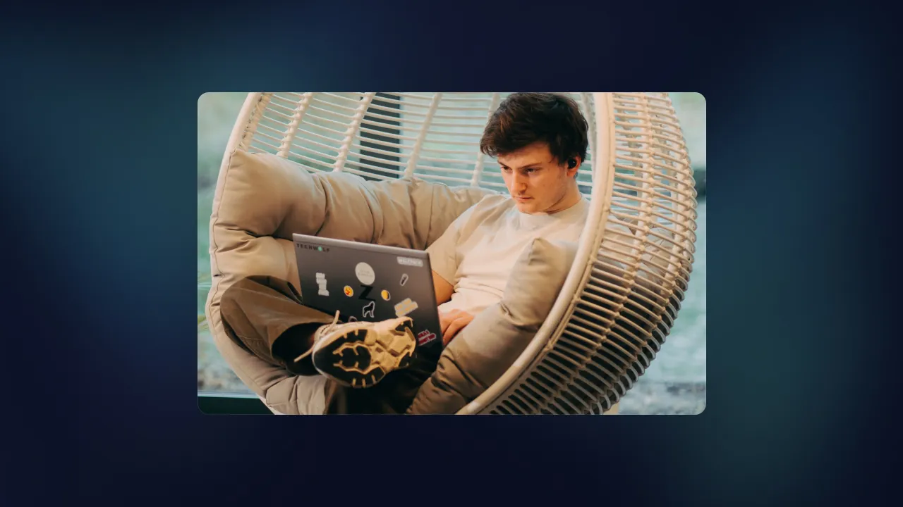 Man working on a TechWolf laptop while sitting in a hanging egg chair outdoors