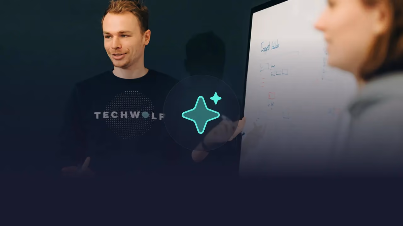Man in a TechWolf sweater at a whiteboard with a colleague, mint AI sparkle icon overlaid
