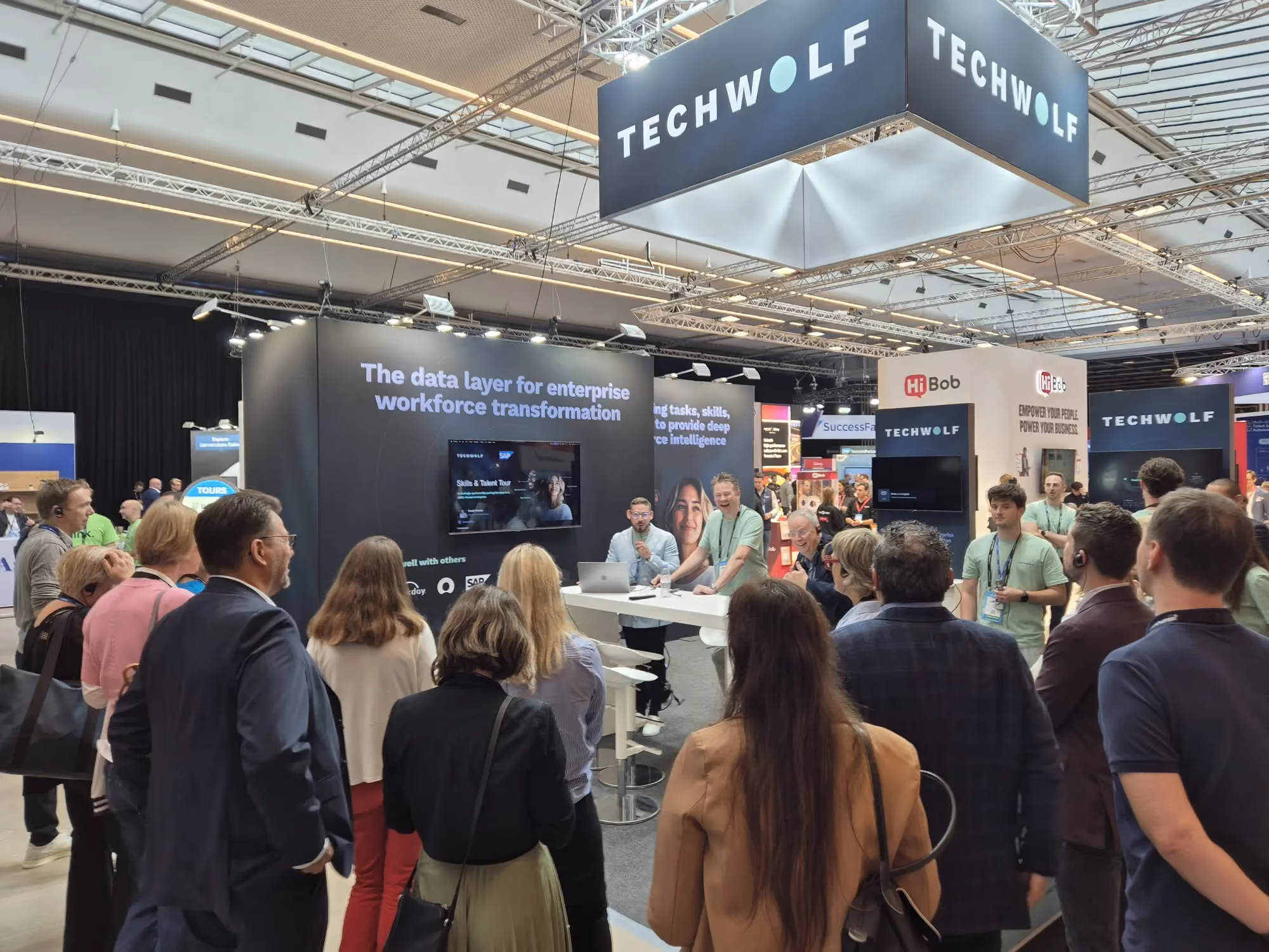 TechWolf trade-show booth with staff in mint T-shirts under a large TECHWOLF sign