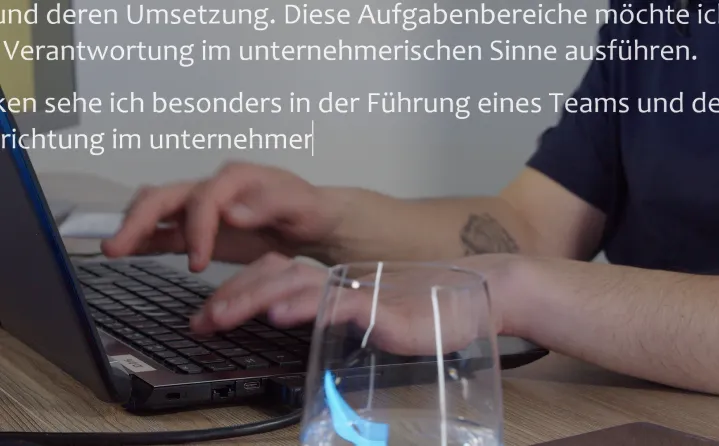 Person, die auf einer Tastatur eines Laptops tippt, mit einem Glas Wasser im Vordergrund und deutschem Text eingeblendet.