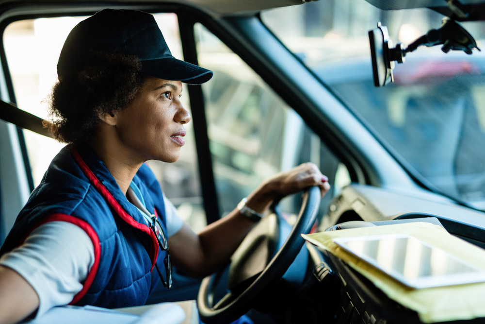 Female HGV driver checking rear view mirror