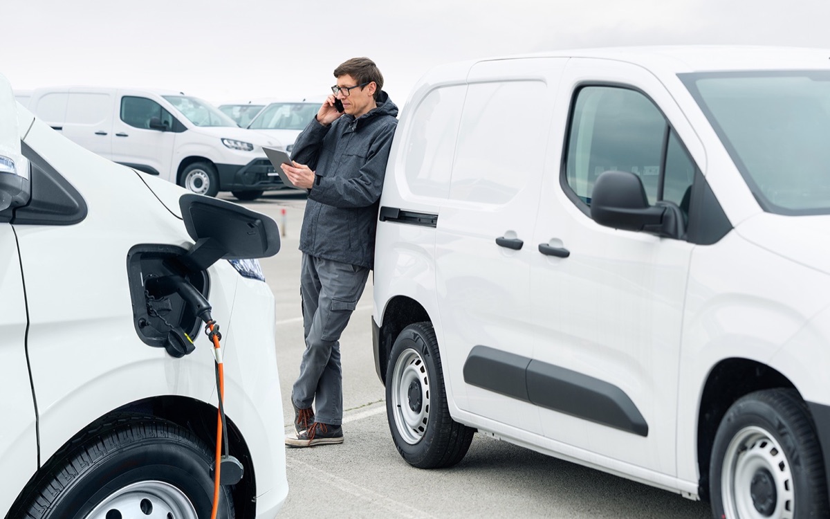 Fleet manager with a tablet among a row of vans