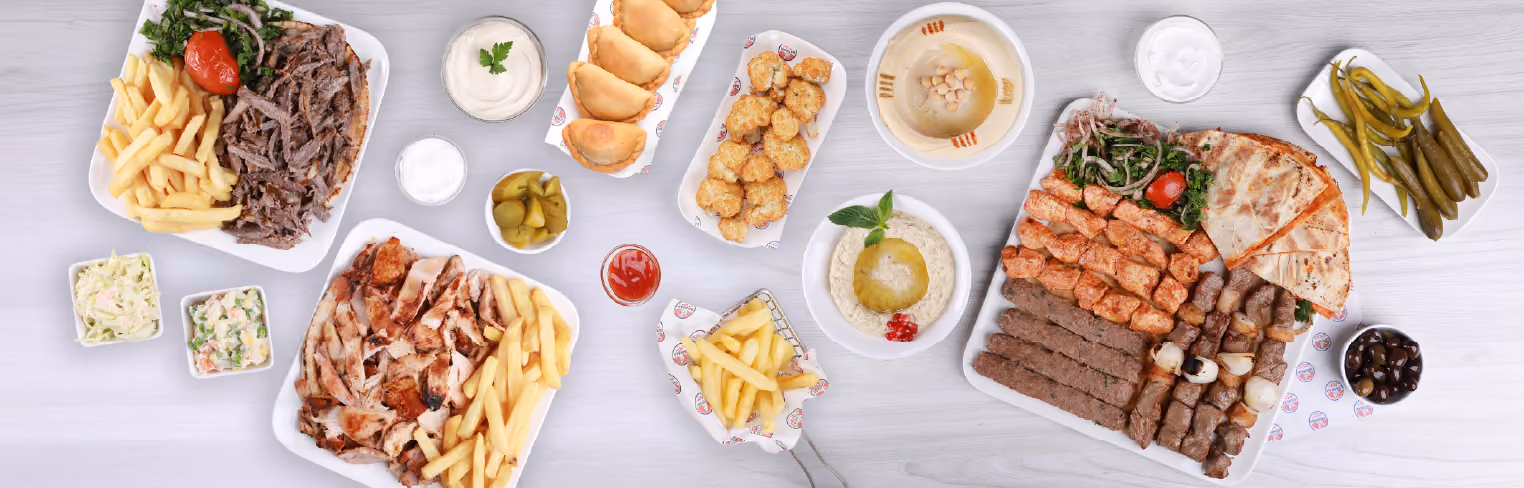 Overhead view of a large spread of Middle Eastern food, including beef and chicken shawarma
